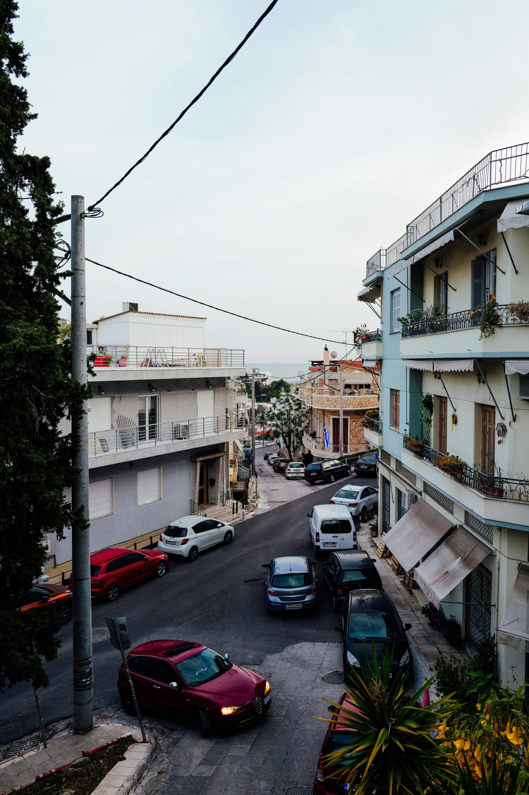 Scenic view of a Mediterranean street with cars and buildings at dusk.